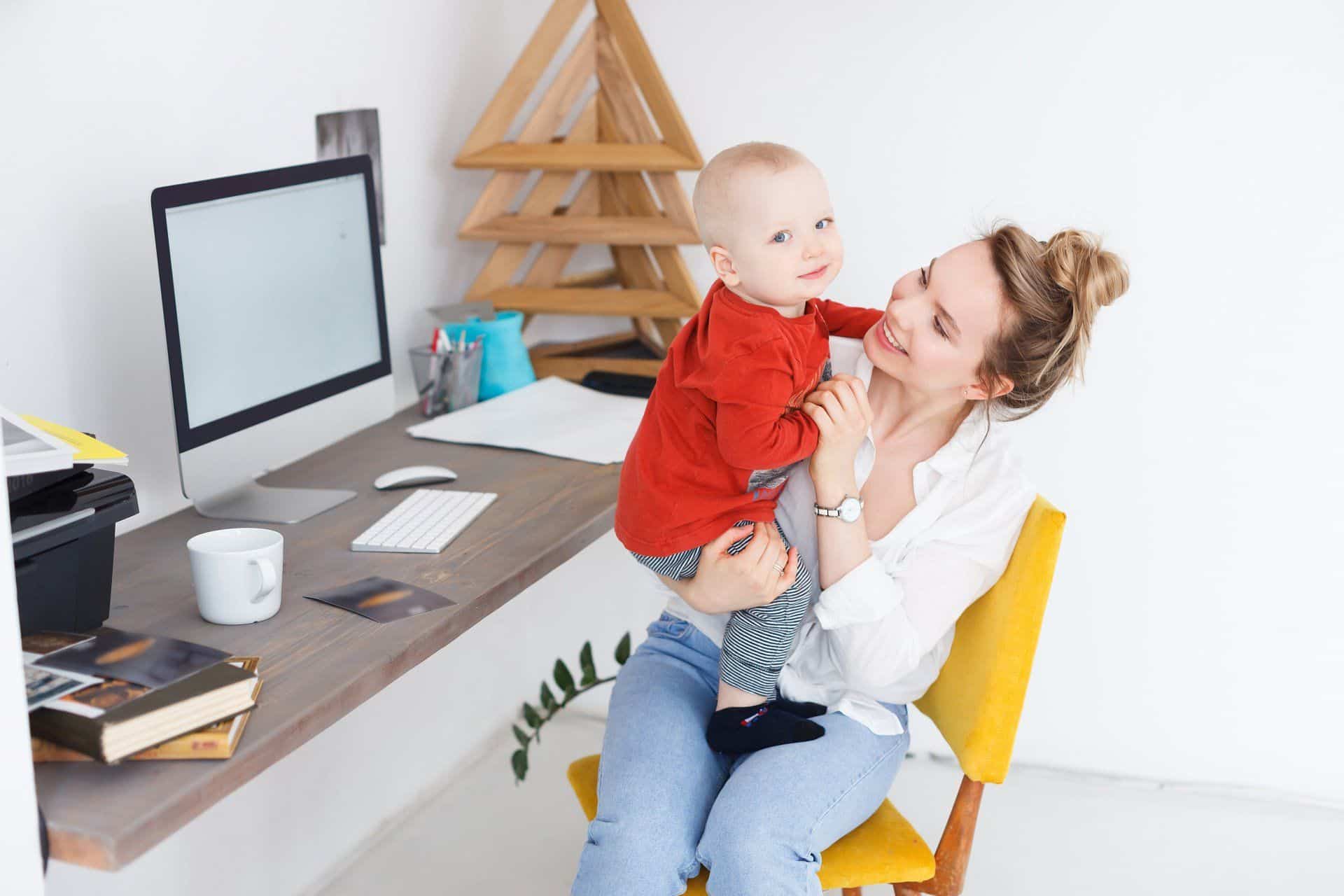 woman working remotely and holding her toddler