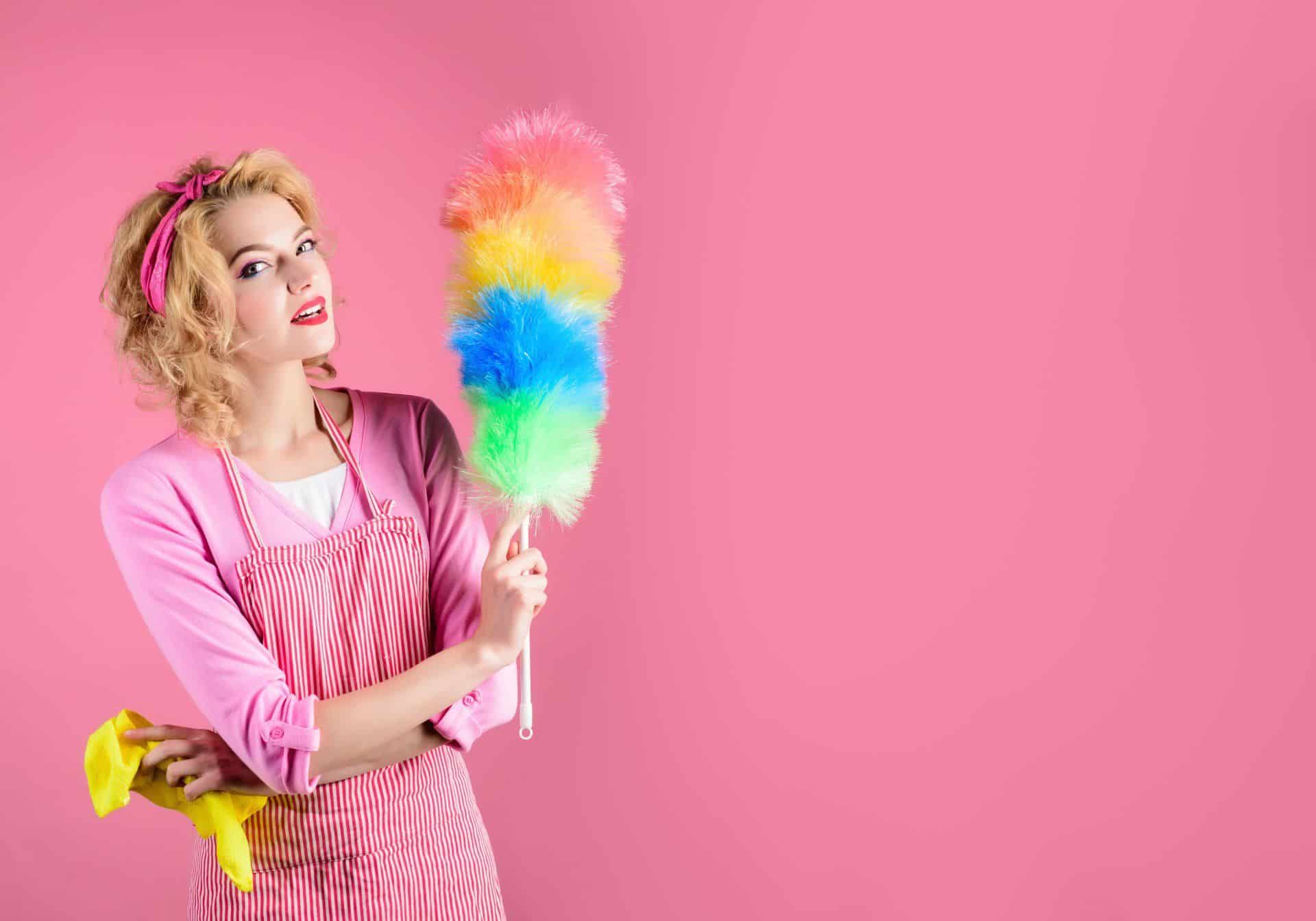 woman dressed in pink holding a rainbow colored feather duster