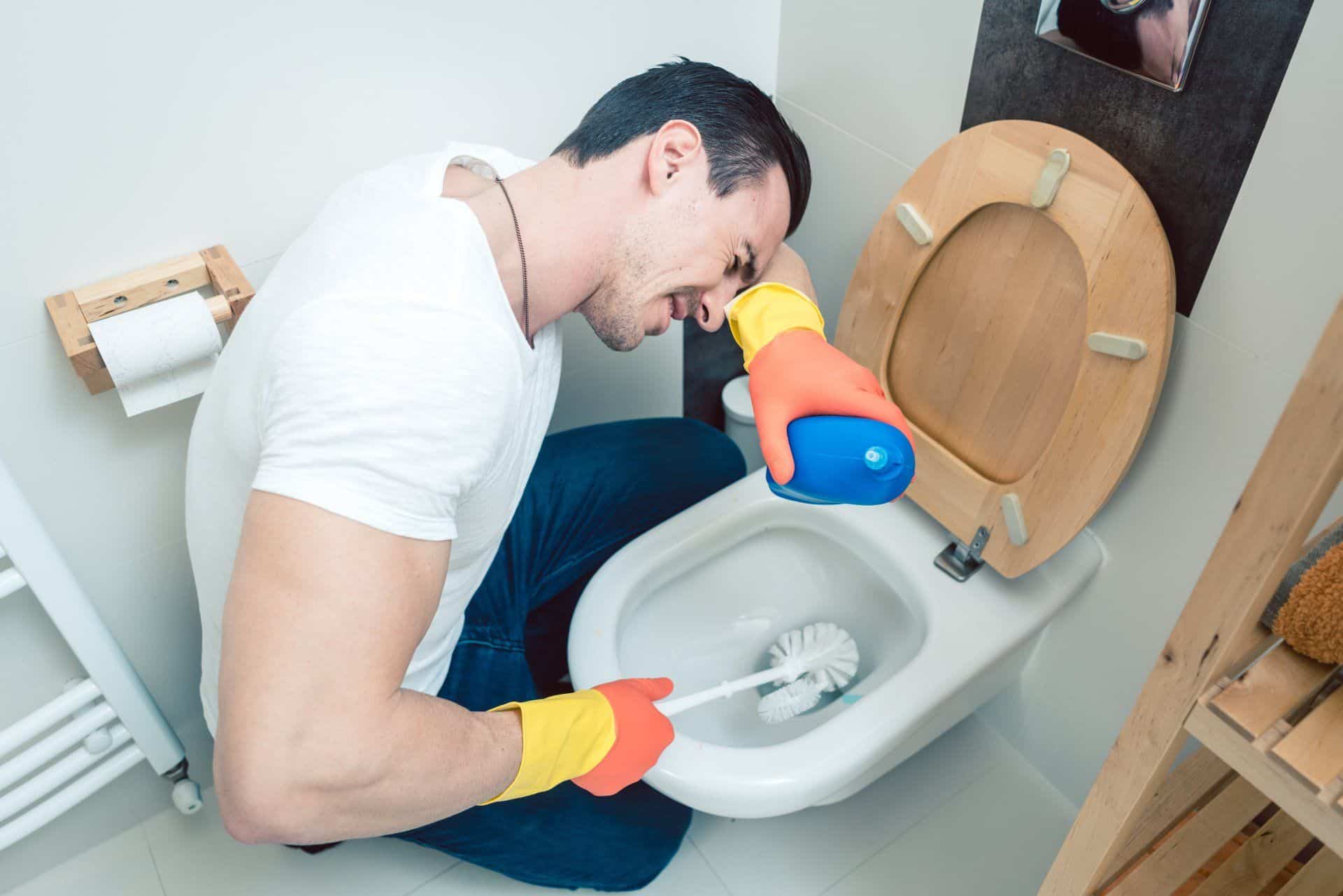 man having a difficult time cleaning a toilet