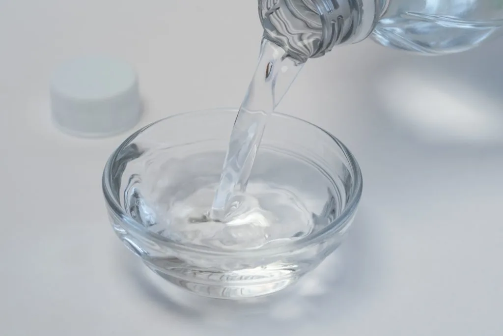 5 Tips to Beat Cabinet Grease Film in the Kitchen 17 Distilled white vinegar being poured into a small glass bowl. Vinegar is great for how to clean grease off kitchen cabinets