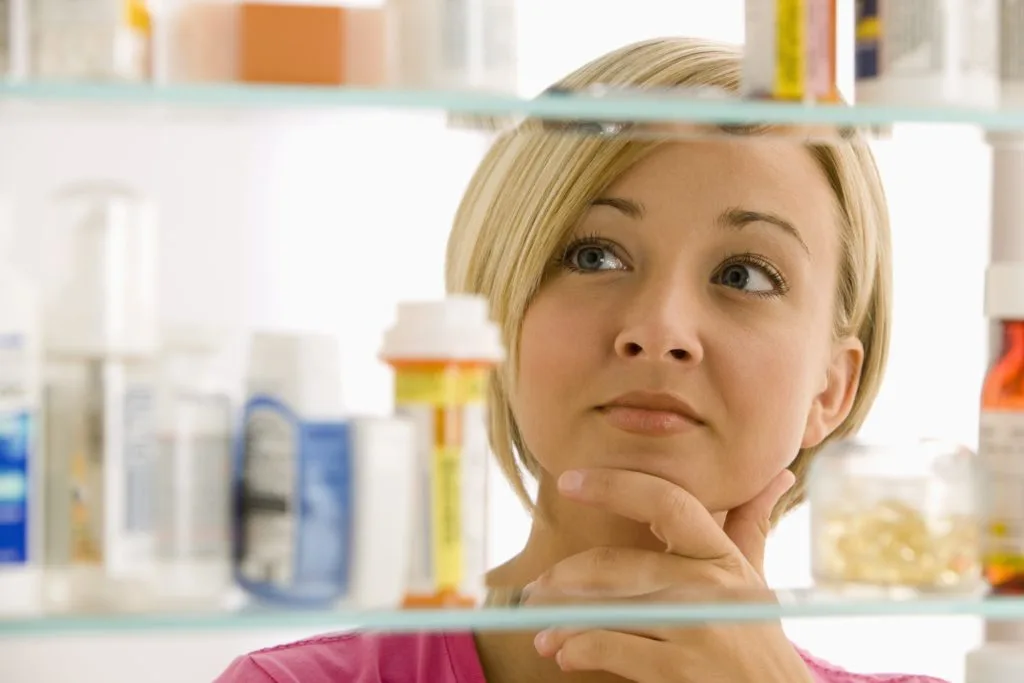 21 Things in Your Home You Should be Throwing Out 14 A young woman is looking through her medicine cabinet.