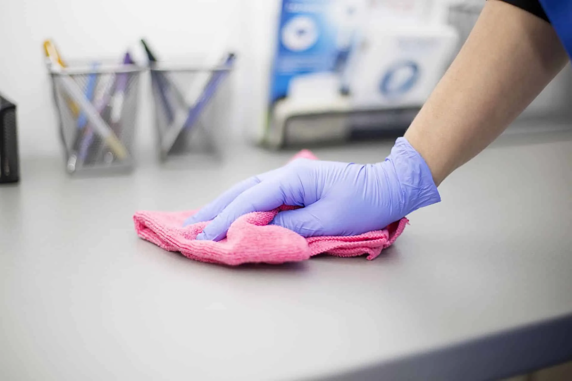 Why Your Office Needs a Commercial Cleaning Service 14 a gloved hand wiping an office desk