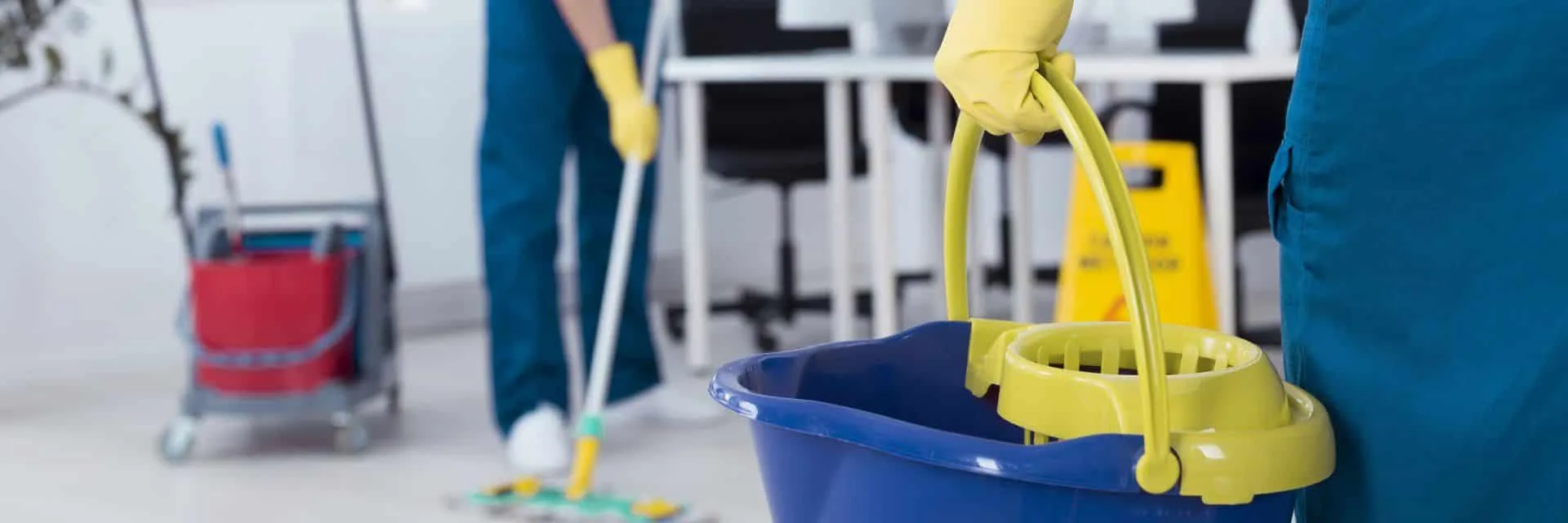 Why Your Office Needs a Commercial Cleaning Service 12 person holding blue cleaning bucket with yellow glove on
