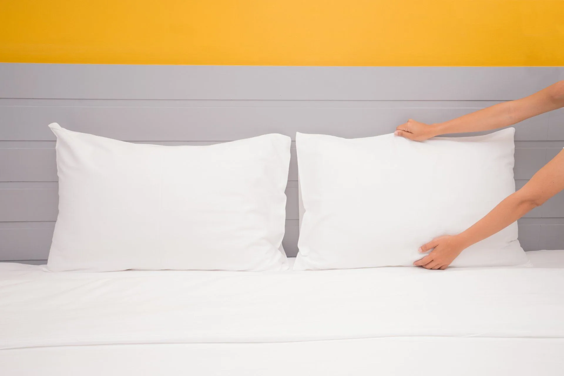 What You Should be Cleaning in Your Home Every Single Day 8 woman fixing white pillows on a bed