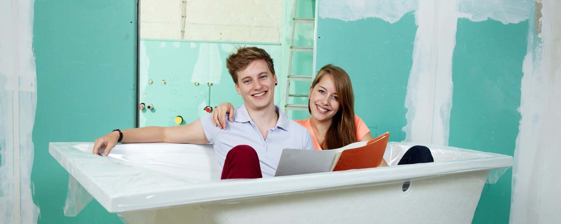 A happy couple sitting in a bathtub in their home that is being remodeled.