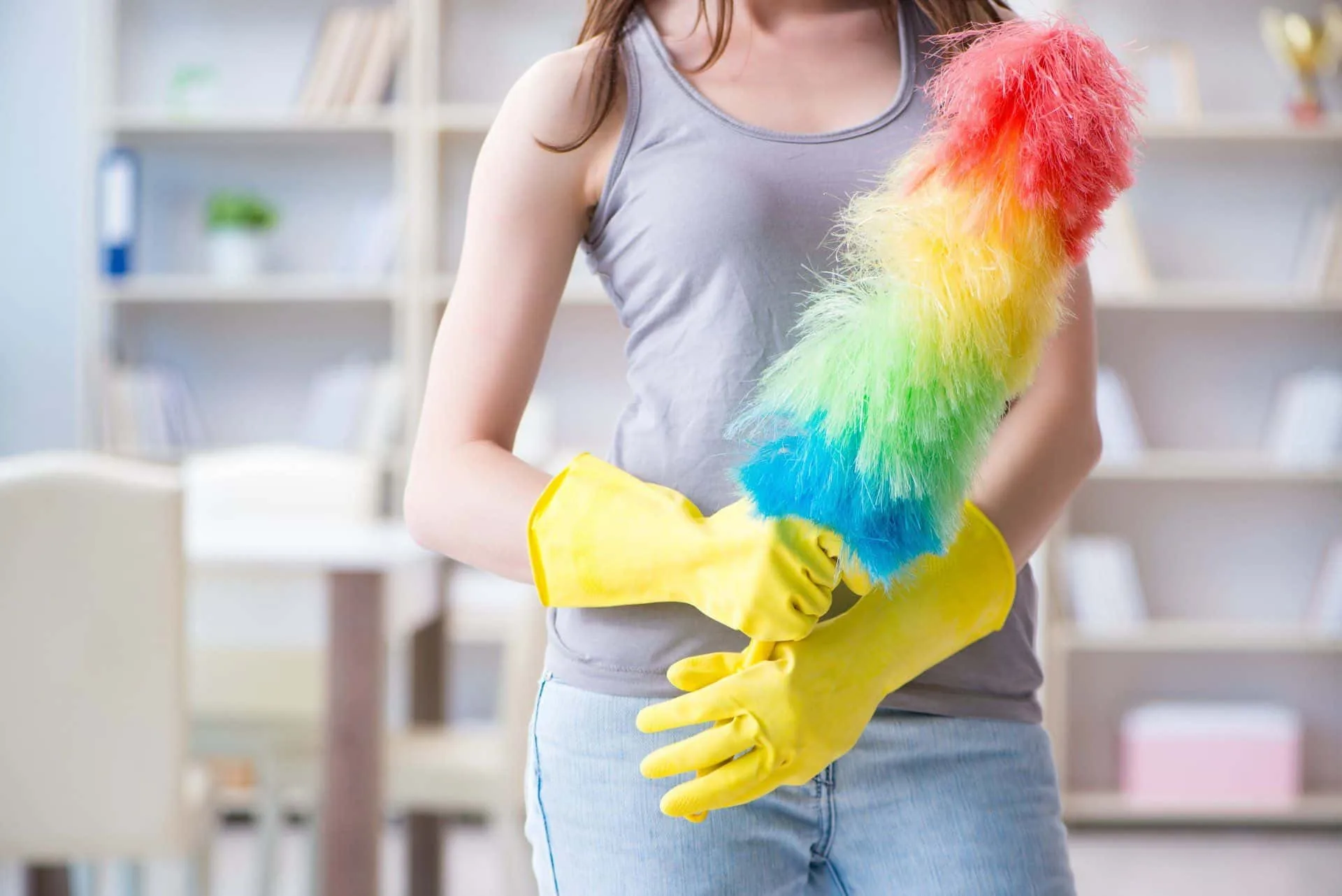 How Often You Should Really Be Dusting Your Home 2 woman in yellow rubber gloves holding a rainbow-colored duster