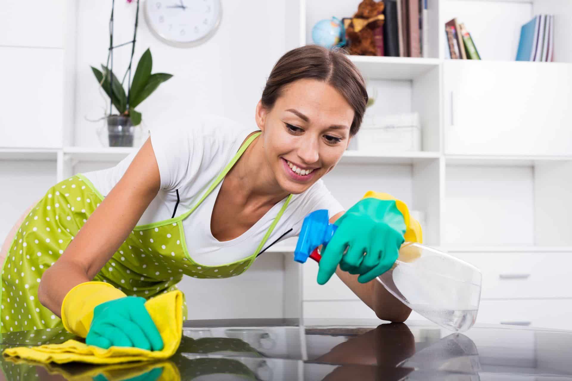 a woman in apron and rubber gloves cleaning a kitchen counter