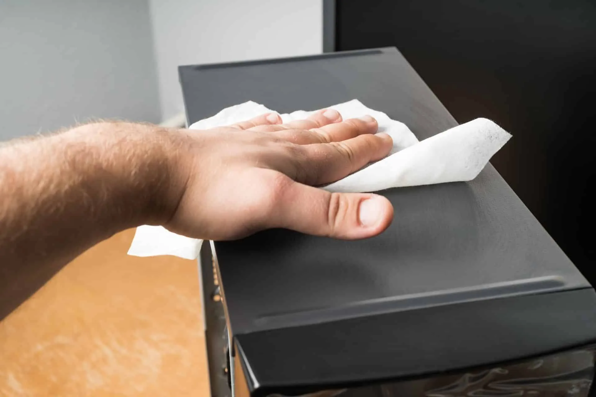 How Often You Should Really Be Dusting Your Home 4 a man dusting a piece of electronic equipment with a damp cloth