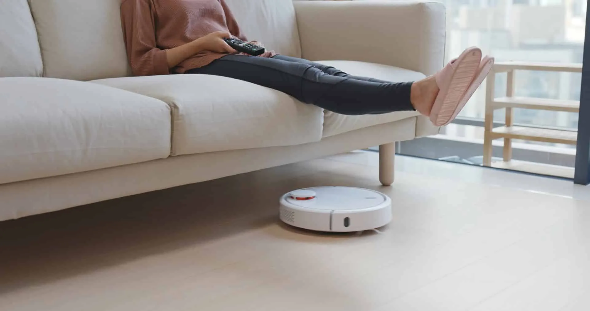 Why Robot Vacuums Can’t Beat Traditional Vacuuming 3 woman watching TV with her feet up while a robotic vacuum runs