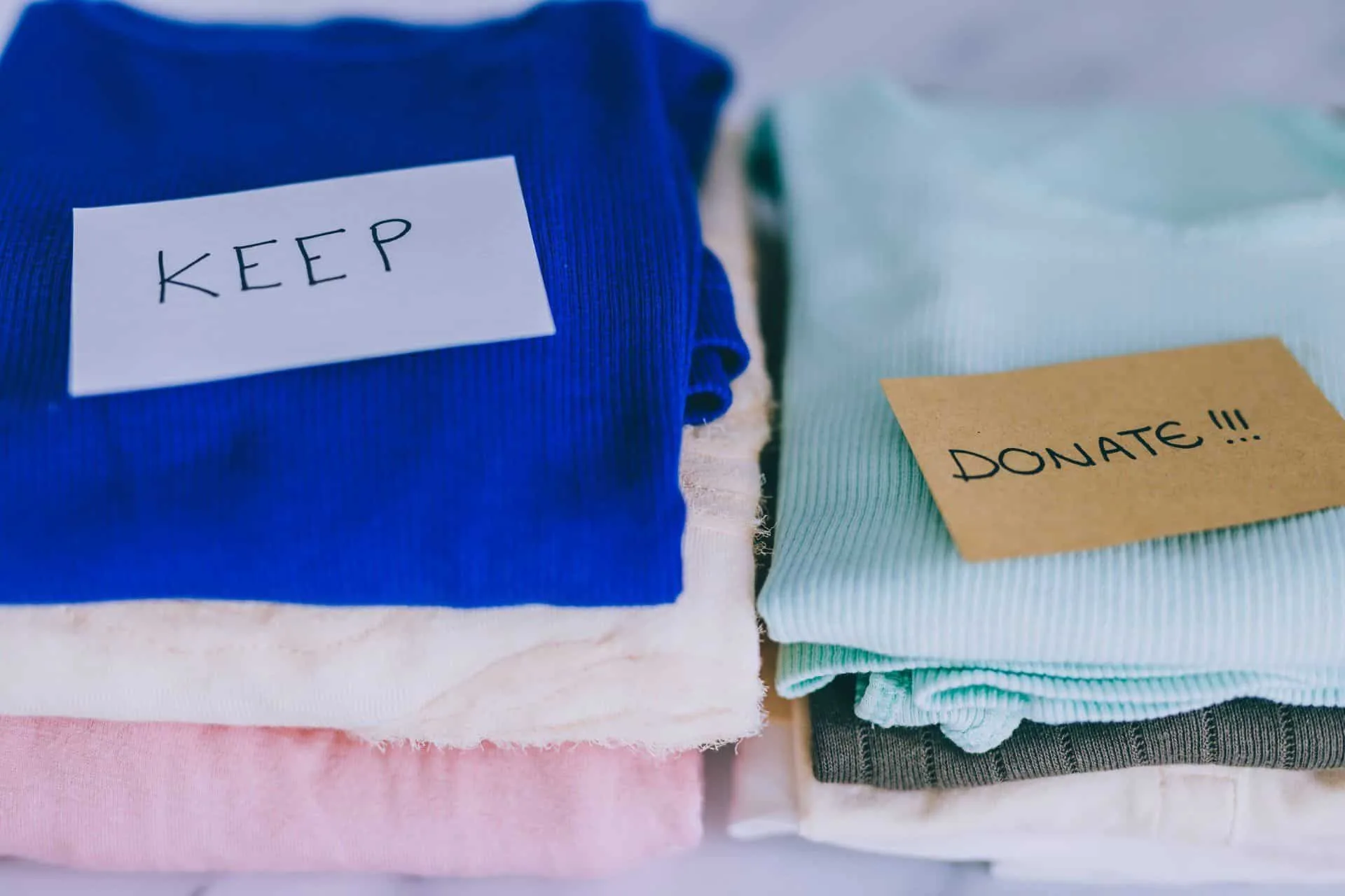 Time To Purge: Ways to Declutter and Reorganize 3 2 piles of folded clothes that say keep and donate