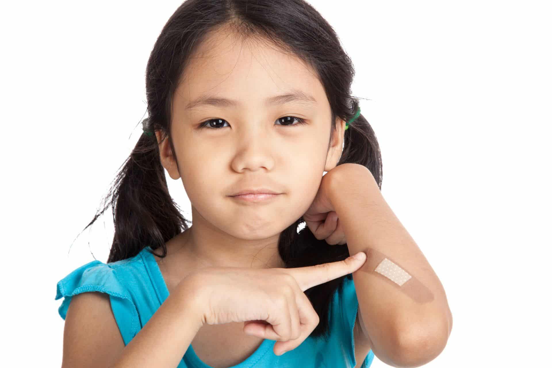 young girl pointing to a band aid on her elbow