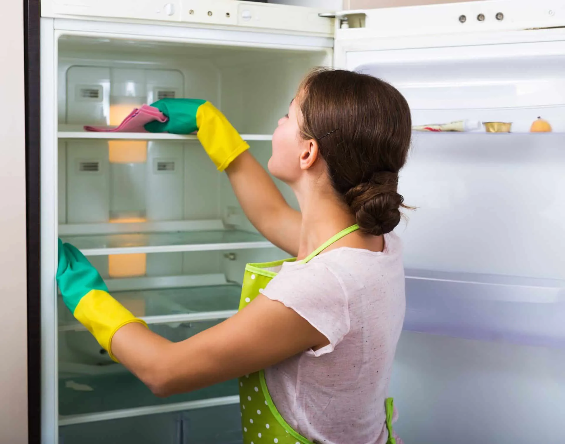 7 Cleaning Resolutions to Start Your New Year Off Right 6 woman wiping down inside of the fridge