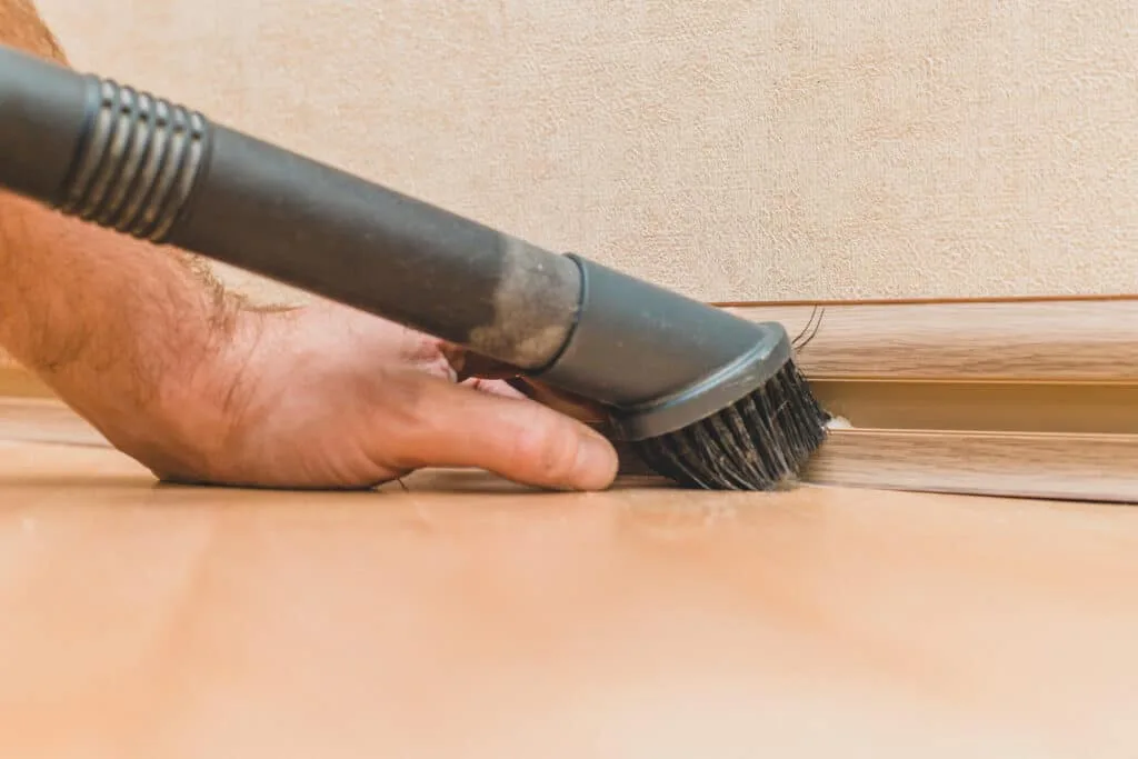 How to Clean Baseboards 7 A man cleaning baseboards with a vacuum attachment