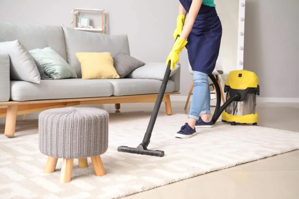 How to Clean Baseboards 5 A professional cleaner using a yellow vacuum to clean an area rug