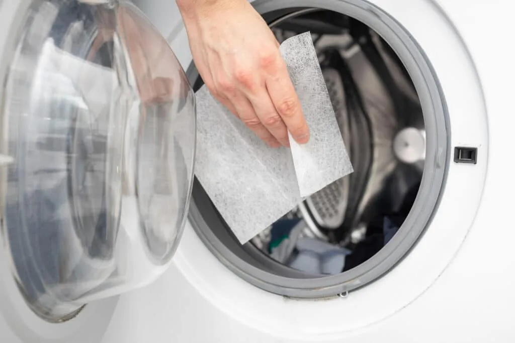 How to Clean Baseboards 9 Someone adding a dryer sheet into a dryer