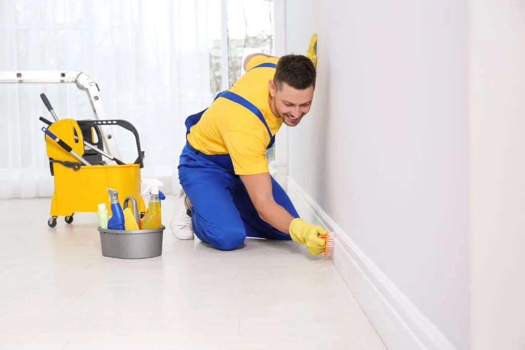 How to Clean Baseboards 14 Professional janitor cleaning baseboard with brush after renovation