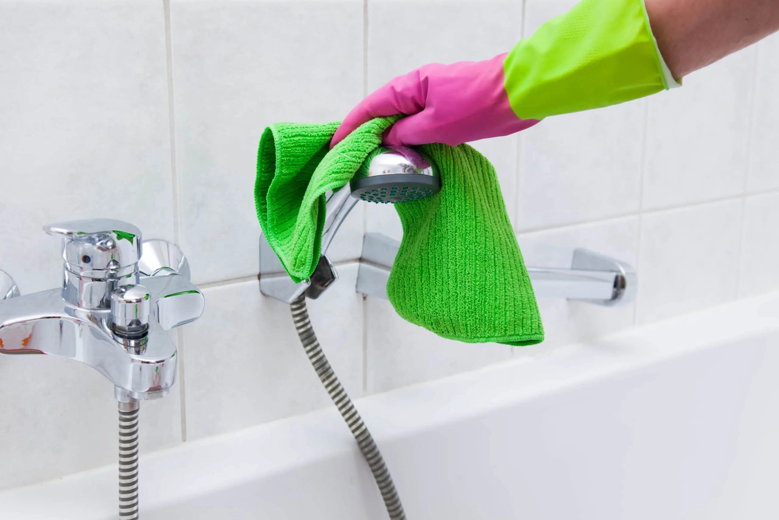 How to Clean a Shower Head 10 Someone in rubber gloves suing a microfiber towel to clean a shower