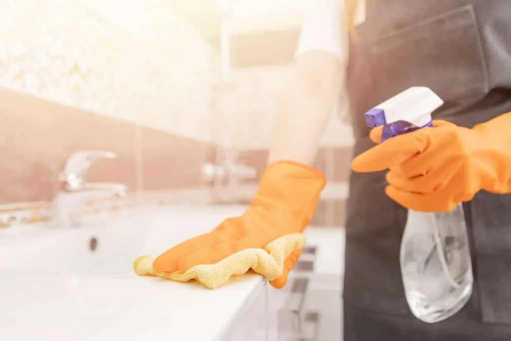 Learn How to Clean a Room in 5 Minutes 5 Someone wearing rubber gloves and spray a bathroom sink to clean it.