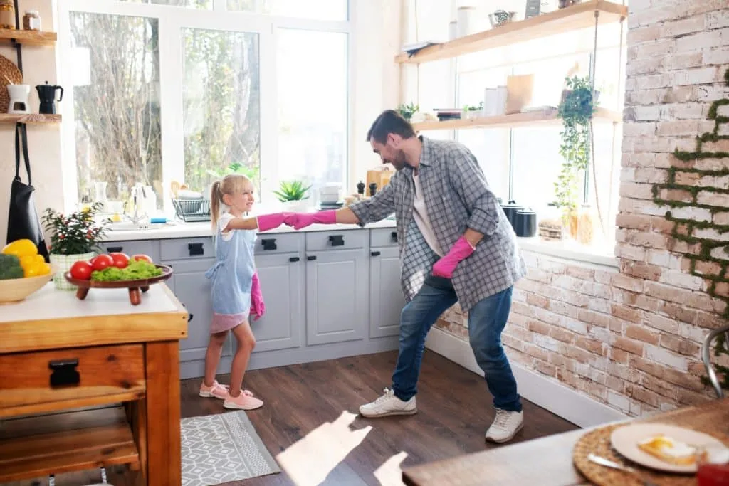 These 7 Chores for Kids Let You Delegate the Housework 9 A daighter and dad working together to clean their kitchen