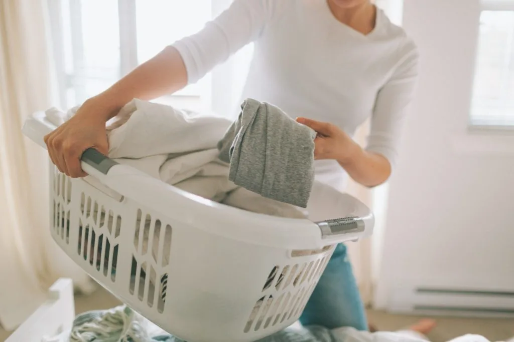 13 Things to Try and Make Cleaning Fun 6 Awoman picking up laundry to tidy a room.